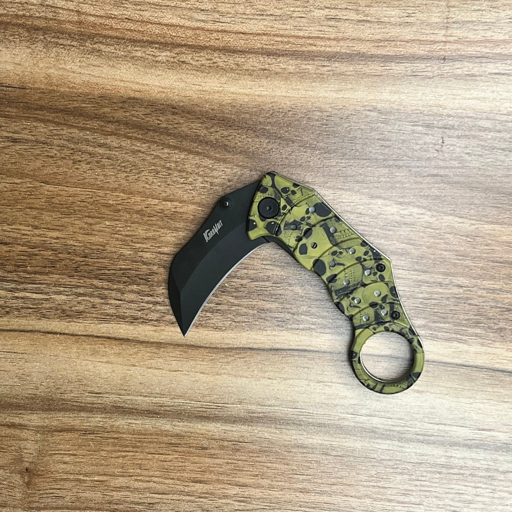 Assisted-opening green karambit knife with a skull-patterned handle and black blade.