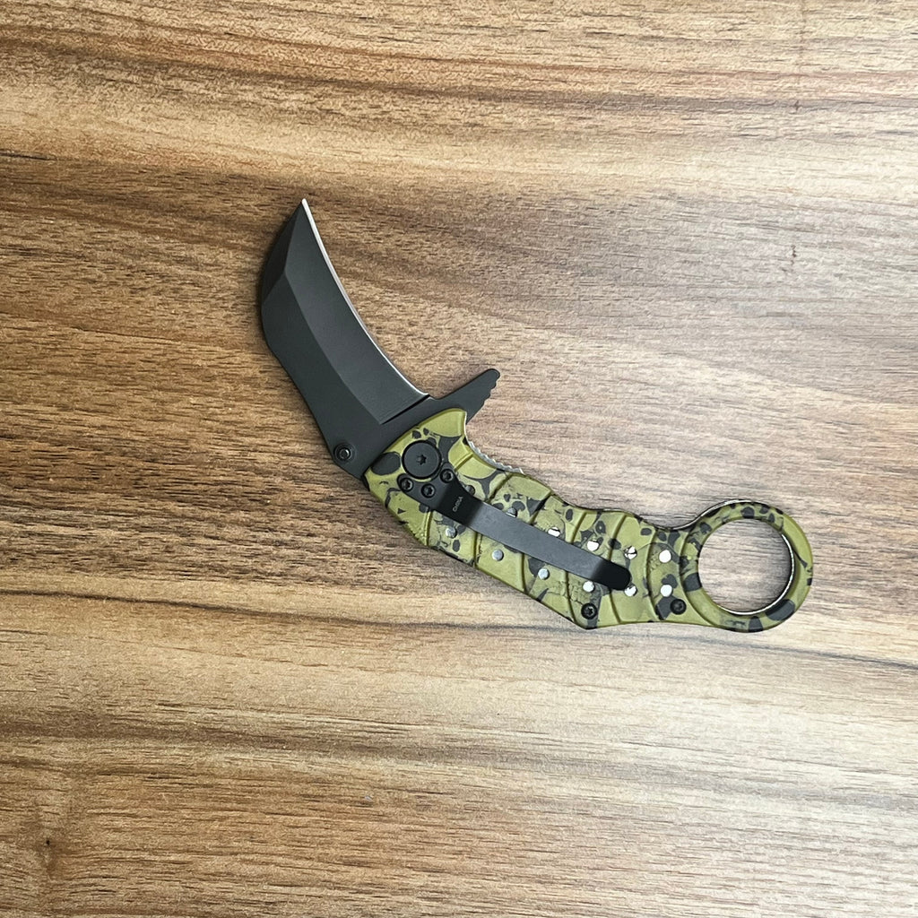 Green karambit tactical knife with a skull-patterned handle and assisted opening.